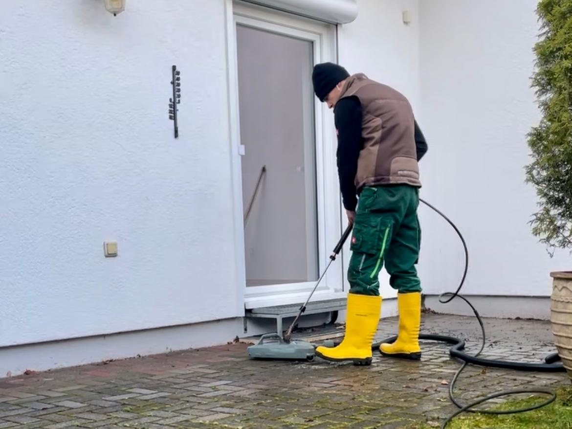 Reinigung einer gepflasterten Eingangsfläche mit Flächenreiniger und niedrigem Druck.